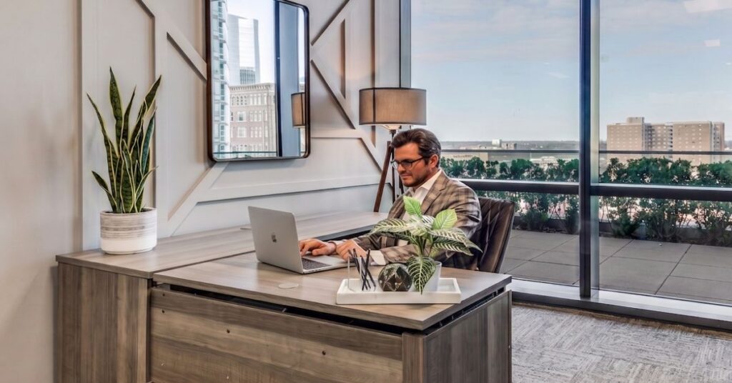 Attorney working at a desk in a furnished private office with floor-to-ceiling windows