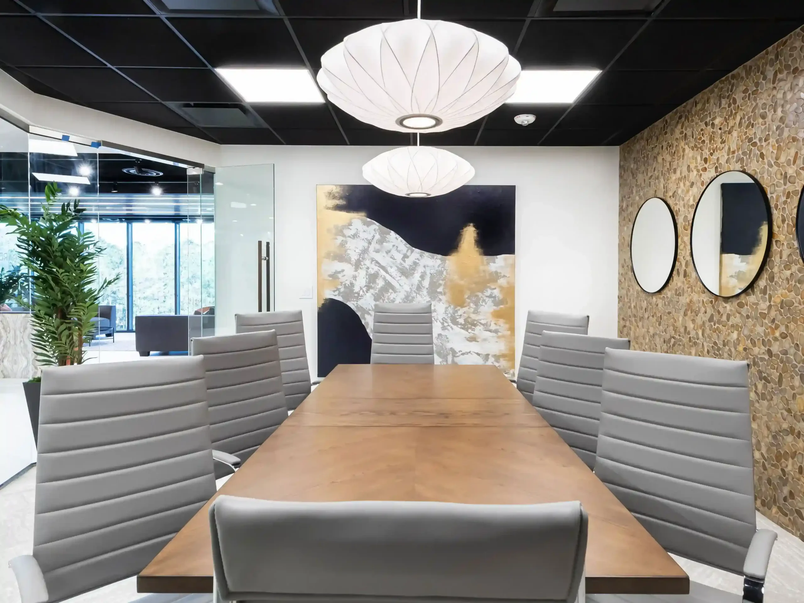 Conference room with a round white pendant light, a gray upholstered feature wall with round mirrors, and gray chairs around a table