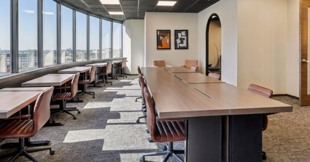 Larger team office with rows of desks along a wall of windows