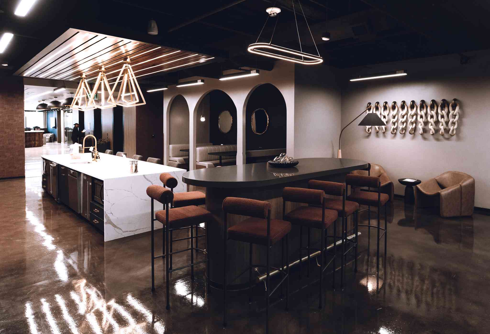 Lounge and cafe area with a bar counter and stools, arched wall niches, and modern ring pendant lighting