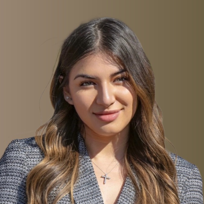 Professional headshot of a woman with long dark hair wearing a gray blazer
